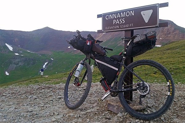 Justin Simoni's bike in front of Cinnamon Pass trail sign 